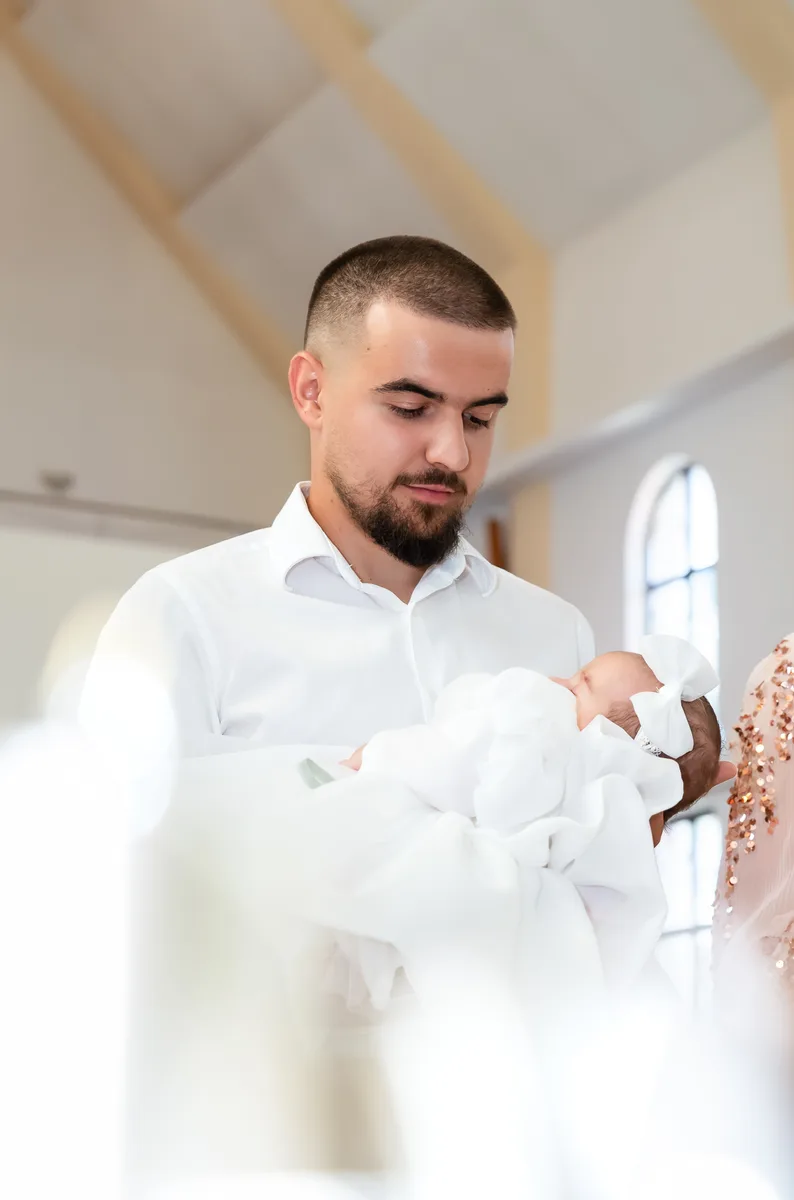 Fotograf botez Roman – tatăl ținând fetița în alb, la Biserica Iisus Bunul Păstor