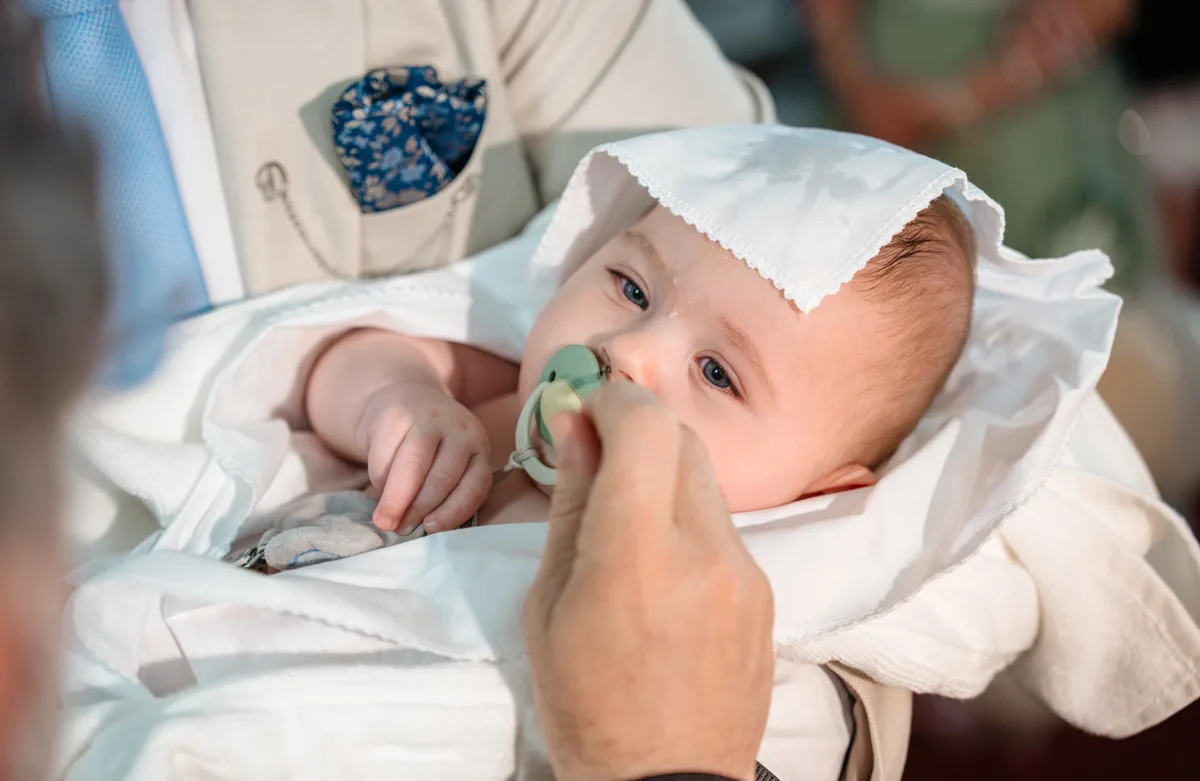 Botez la Biserica Sfinții Voievozi din Roman – bebeluș învelit în pânză albă după scufundare